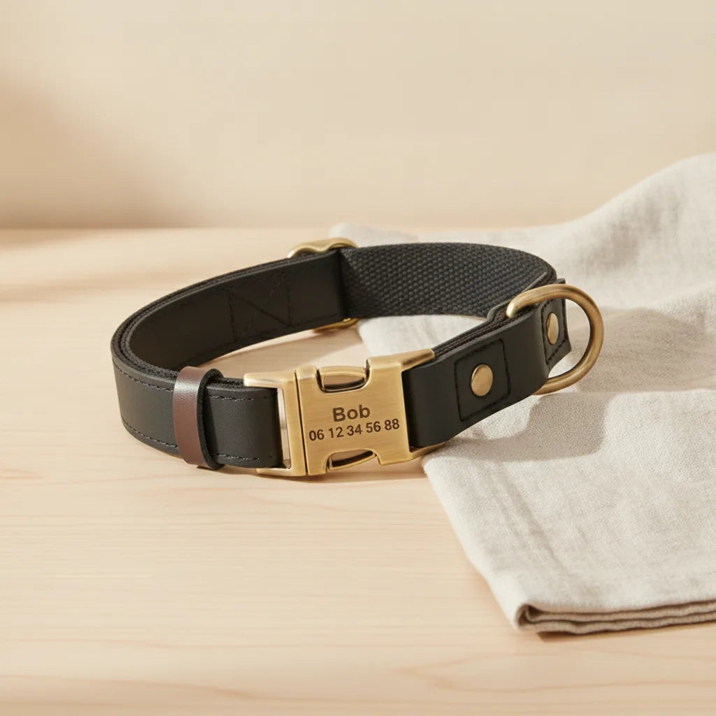 Collier pour chien en cuir noir personnalise avec plaque gravee, pose sur une table en bois